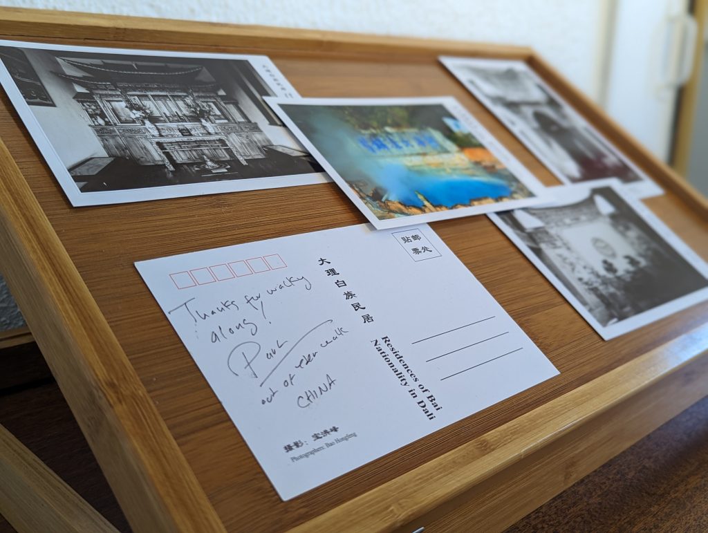 Postcards are arranged on a desk. One is signed with a thank you message.